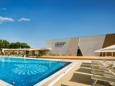 Piscina y fachada moderna en Bella Vista Chalet, Valamar Camping Istra, Croacia, bajo un cielo soleado.