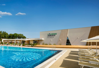 Zwembad en modern gebouw bij Bella Vista Chalet op Valamar Camping Istra, Kroatië, bij zonnig weer.