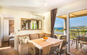 Moderne lodge woonkamer met eetruimte, sofa en balkon met uitzicht op zee en het landschap buiten.