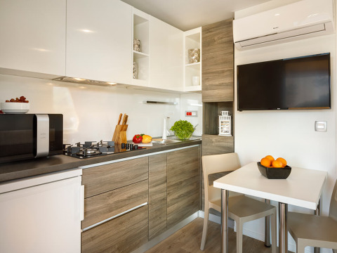 Cocina moderna y comedor en Bella Vista Chalet del Valamar Camping Istra en Croacia, con televisor y electrodomésticos.