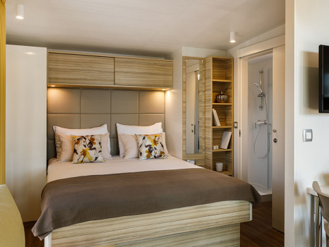 Dormitorio moderno con cama doble, cojines acogedores y baño privado en Bella Vista Chalet, Valamar Camping Istra.