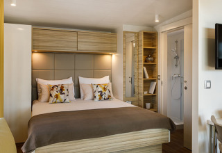 Dormitorio moderno con cama doble, cojines acogedores y baño privado en Bella Vista Chalet, Valamar Camping Istra.