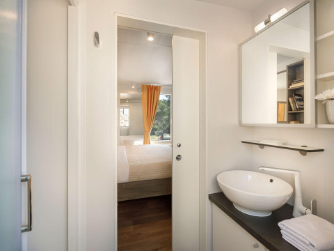 Vista desde el baño hacia el dormitorio con cortina amarilla en Bella Vista Chalet, Valamar Camping Istra, Croacia.