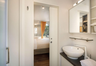 Vista desde el baño hacia el dormitorio con cortina amarilla en Bella Vista Chalet, Valamar Camping Istra, Croacia.