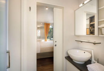 Vue de la salle de bain sur la chambre avec rideau jaune au Bella Vista Chalet, Valamar Camping Istra, Croatie.