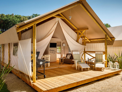 Sunset Premium Glamping Tent met houten terras, luxe lounge stoelen en sfeervolle buitenomgeving.
