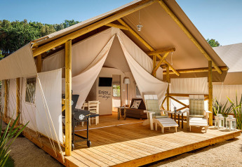 Tienda de glamping Sunset Premium con terraza de madera, cómodas sillas y ambiente relajante al aire libre.