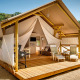 Tienda de glamping Sunset Premium con terraza de madera, cómodas sillas y ambiente relajante al aire libre.