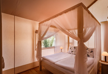 Camera luminosa nella Sunset Premium Glamping Tent al Valamar Camping Istra in Croazia, con letto a baldacchino.