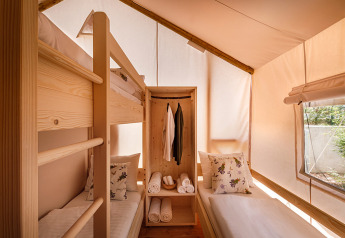 Interior de una tienda glamping con literas, cama individual y ventana en Valamar Camping Istra en Croacia.