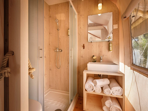 Moderne badkamer in safari glamping tent met douche, wastafel en handdoeken bij Valamar Camping Istra, Kroatië.