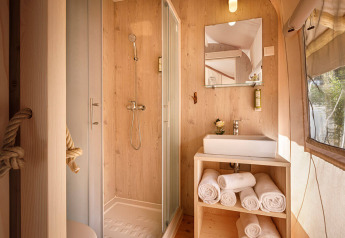 Bagno moderno in tenda safari glamping con doccia, lavandino e asciugamani al Valamar Camping Istra, Croazia.