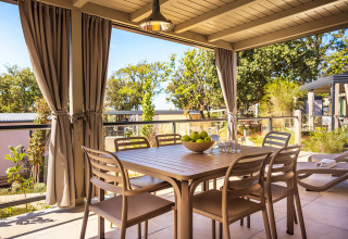 Buiten eetgedeelte bij Bella Vista Home in Valamar Camping Istra, Kroatië, met tafel, stoelen en gordijnen.