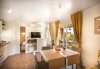 Helles, modernes Wohnzimmer in der Bella Vista Home Lodge mit Esstisch, TV und Terrasse.