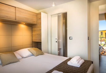 Modernes Schlafzimmer in der Bella Vista Home Lodge mit Doppelbett, Holzmöbeln und Tageslicht.