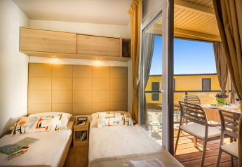 Gemütliches Schlafzimmer mit zwei Einzelbetten im Bella Vista Home und Zugang zu einer sonnigen Terrasse mit Tisch.