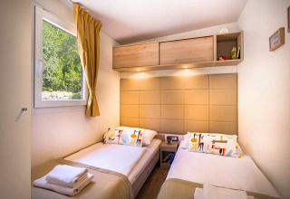 Moderne tweepersoonskamer met groot raam, sfeerverlichting en opbergruimte in Bella Vista Home, Valamar Camping Istra, Kroatië.