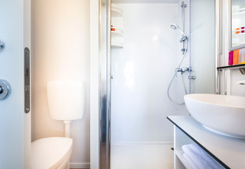Baño moderno y compacto en Bella Vista Home lodge con ducha, inodoro y lavabo elegante.