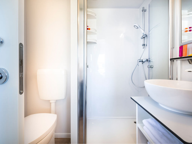 Baño moderno y compacto en Bella Vista Home lodge con ducha, inodoro y lavabo elegante.