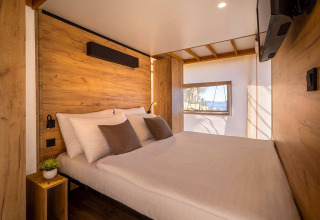 Slaapkamer interieur in een safaritent met houten muren, modern design en raam met mooi uitzicht.