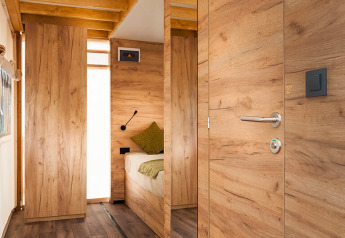 Vista interna di una moderna tenda safari con pannelli in legno, pavimento in legno e zona letto accogliente.