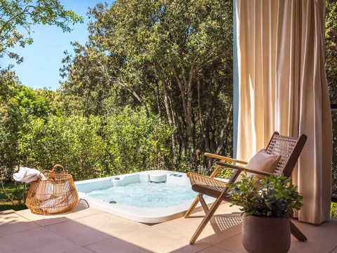 Buitenjacuzzi en comfortabele stoel bij Sunset Villa, Valamar Camping Istra, omringd door bomen in Kroatië.