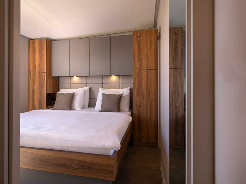 Moderne slaapkamer met houten panelen, gezellige verlichting en groot bed in Sunset Villa met jacuzzi, Kroatië.