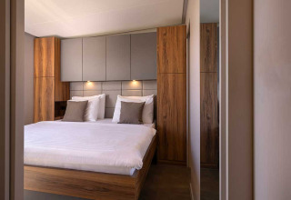 Moderne slaapkamer met houten panelen, gezellige verlichting en groot bed in Sunset Villa met jacuzzi, Kroatië.