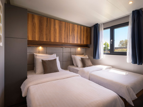 Slaapkamer met twee eenpersoonsbedden, houten kasten en raam in Sunset Villa met jacuzzi, Valamar Camping Istra, Kroatië.