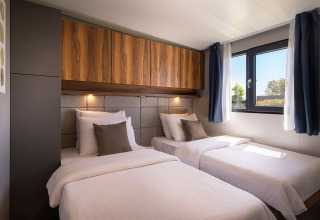 Slaapkamer met twee eenpersoonsbedden, houten kasten en een raam in Sunset Villa met jacuzzi, Valamar Camping Istra, Kroatië.