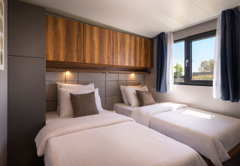 Camera da letto con due letti singoli, armadi in legno e finestra alla Sunset Villa con jacuzzi, Valamar Camping Istra, Croazia.