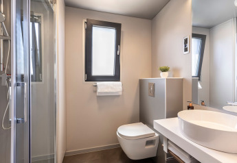 Bagno moderno con WC sospeso, lavabo rotondo e doccia alla Sunset Villa, Valamar Camping Istra, Croazia.