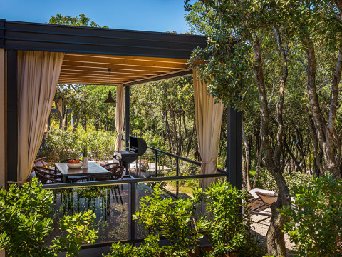 Buitenterras met eettafel en barbecue bij Sunset Villa met jacuzzi, omringd door bomen in Valamar Camping Istra.