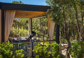 Buitenterras met eettafel en barbecue bij Sunset Villa met jacuzzi, omringd door bomen in Valamar Camping Istra.