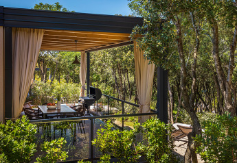 Terrasse extérieure avec coin repas et barbecue à Sunset Villa avec jacuzzi, entourée d’arbres au Valamar Camping Istra.