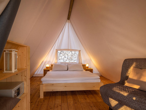 Binnenkant van Sunset Bell Tent Seaview bij Valamar Camping Istra, Kroatië, met gezellig bed en houten vloer.