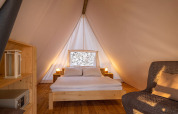 Interior de la Sunset Bell Tent Seaview en Valamar Camping Istra, Croacia, con cama acogedora y suelo de madera.