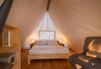 Interno della Sunset Bell Tent Seaview al Valamar Camping Istra in Croazia con letto accogliente e pavimento in legno.