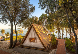 Das Sunset Bell Tent Seaview Safari-Zelt am Valamar Camping Istra in Kroatien, nah am Wasser und von Bäumen umgeben.