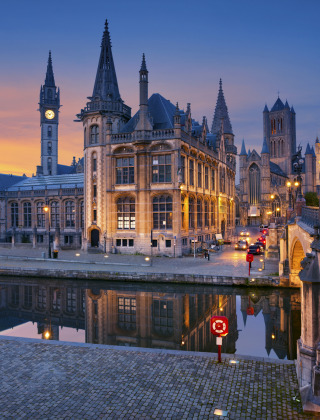 Avondzicht op een schilderachtige Europese stad met kanaal en verlichte historische gebouwen bij zonsondergang.