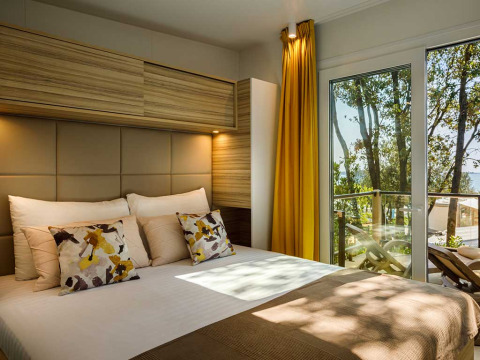 Moderne slaapkamer bij Istra Home op Valamar Camping Istra in Kroatië met groot bed en zicht op het balkon.