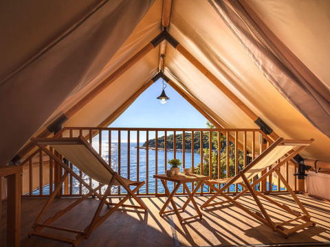 Safaritent met houten stoelen en tafel, uitzicht op zee bij Sunset Glamping Tent Seaview, Valamar Camping Istra, Kroatië.