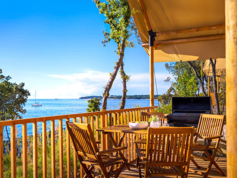Houten terras met tuinmeubilair en barbecue aan Sunset Glamping Tent Seaview bij Valamar Camping Istra, Kroatië.