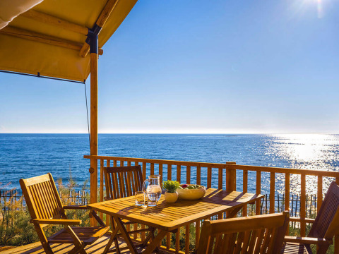 Wooden terrace with sea view at Sunset Glamping Tent Seaview in Valamar Camping Istra, Croatia, on a sunny day.