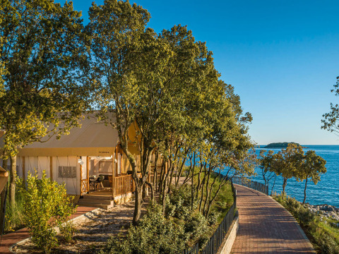 Safari tent Sunset Glamping Tent Seaview bij Valamar Camping Istra in Kroatië met zeezicht en omringd door bomen.