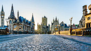 Kasseienstraat met indrukwekkende historische gebouwen in het centrum van Gent, België bij zonsopgang.
