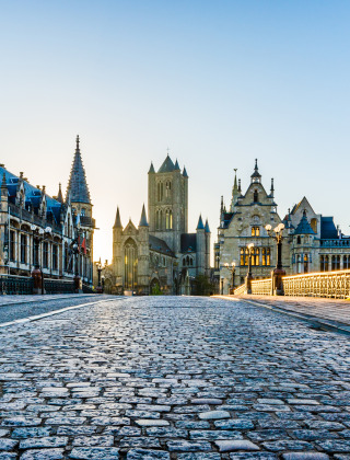 Cobblestone street and beautiful medieval buildings in the historic center of Ghent, Belgium at dawn.