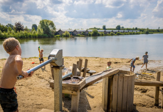 Børn leger på en sandstrand ved en sø i Familievakantiepark Krieghuusbelten i Overijssel, Holland.
