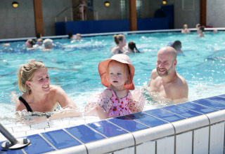 Familie mit Kind entspannt sich im Schwimmbad im Familievakantiepark Krieghuusbelten, Overijssel.