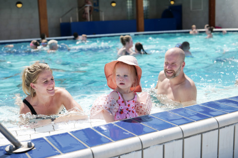 Famiglia con bambino si diverte in piscina al Familievakantiepark Krieghuusbelten, Overijssel, Paesi Bassi.